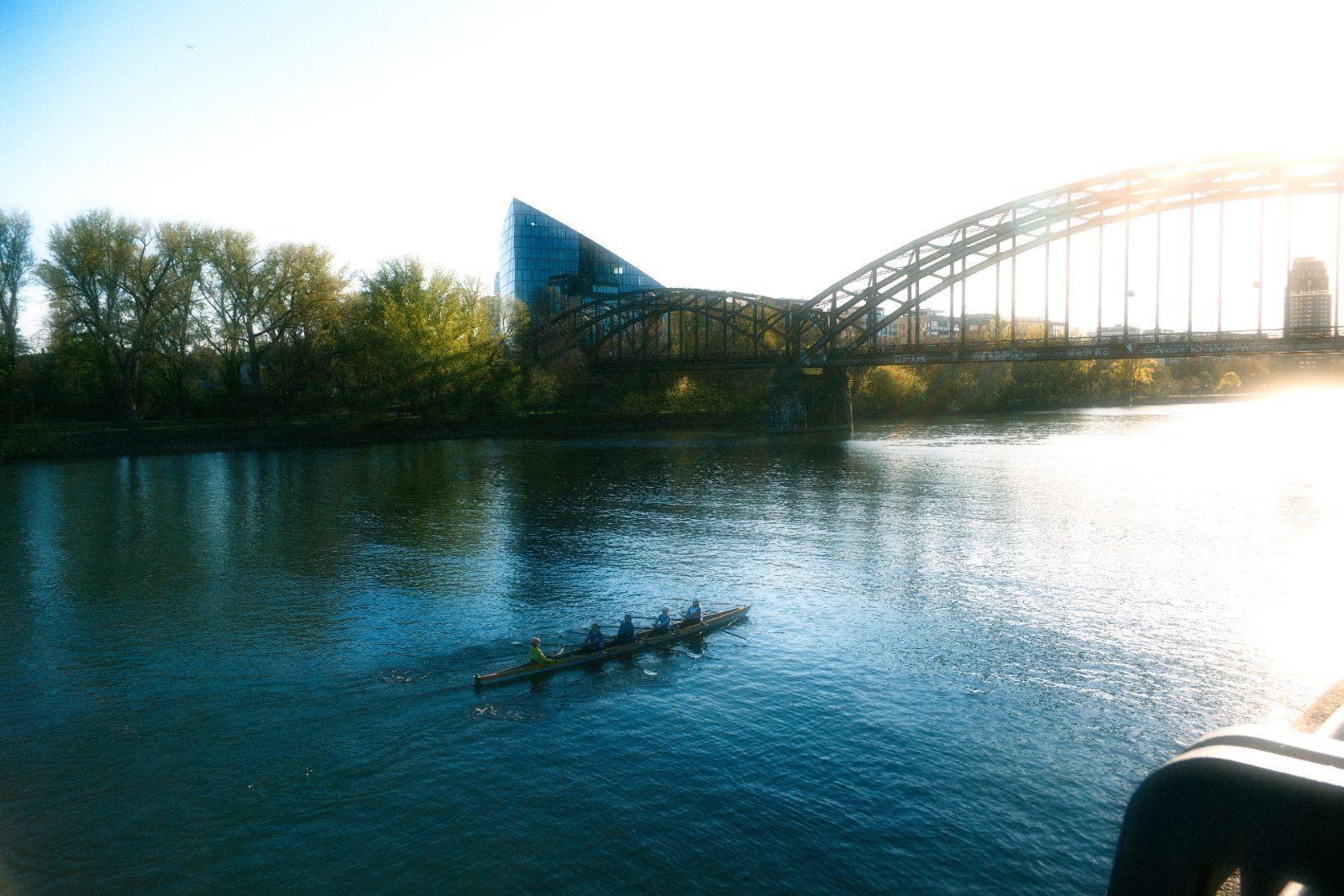 Ruderboot auf dem Main vor einer eisernen Brücke im Morgenlicht
