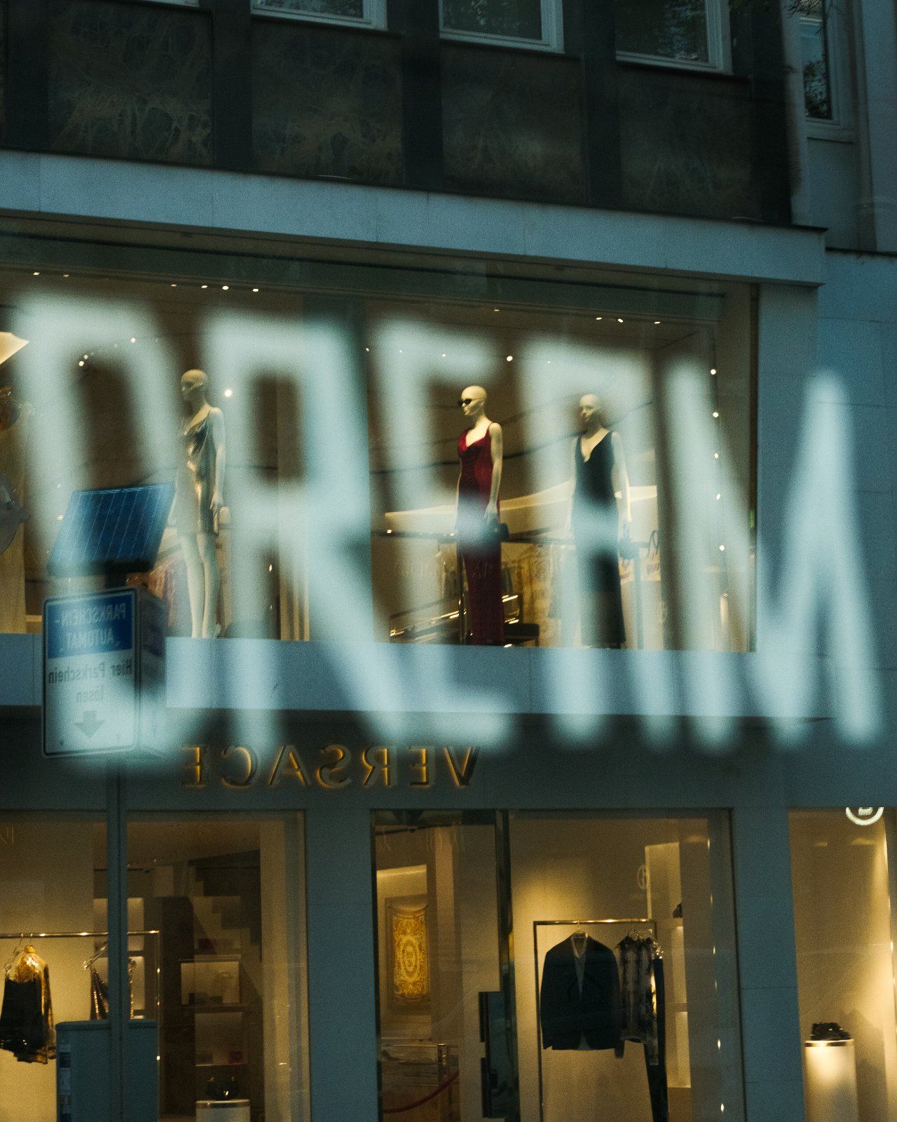 Spiegelung eines Schriftzugs im Schaufenster einer Versace-Filiale bei Nacht