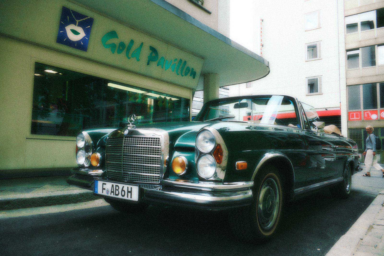 Grüner Oldtimer-Mercedes-Cabrio parkt vor dem Geschäft 'Gold Pavillon' in der Stadt